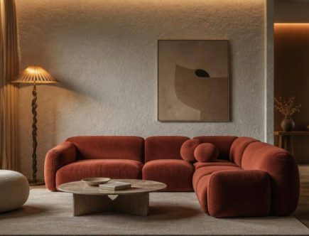Soggiorno contemporaneo con divano, superfici materiche e illuminazione studiata.