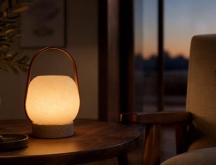 Piccola lampada portatile in ceramica illumina un tavolino accanto a una poltrona.
